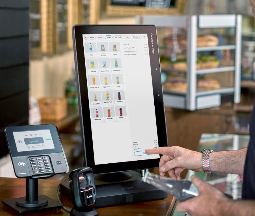 Person using a touchscreen point-of-sale system with a beverage selection menu in a cafe with a payment terminal nearby.
