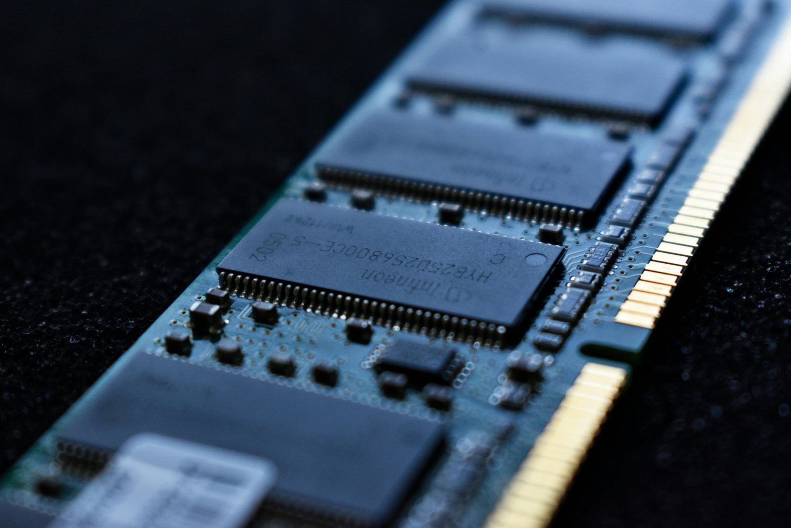 Close-up of a computer RAM module showing memory chips and gold connector pins.
